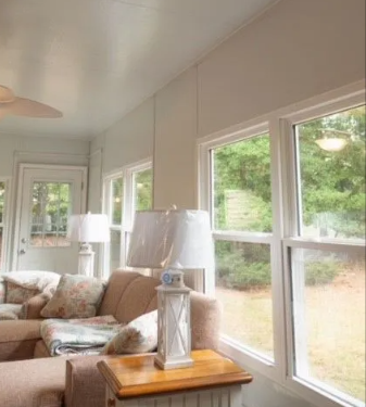 Sunroom interior with windows, sofa, lamps, and a small wooden table.