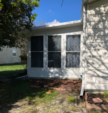 White building with three large windows; green grass, clear sky.