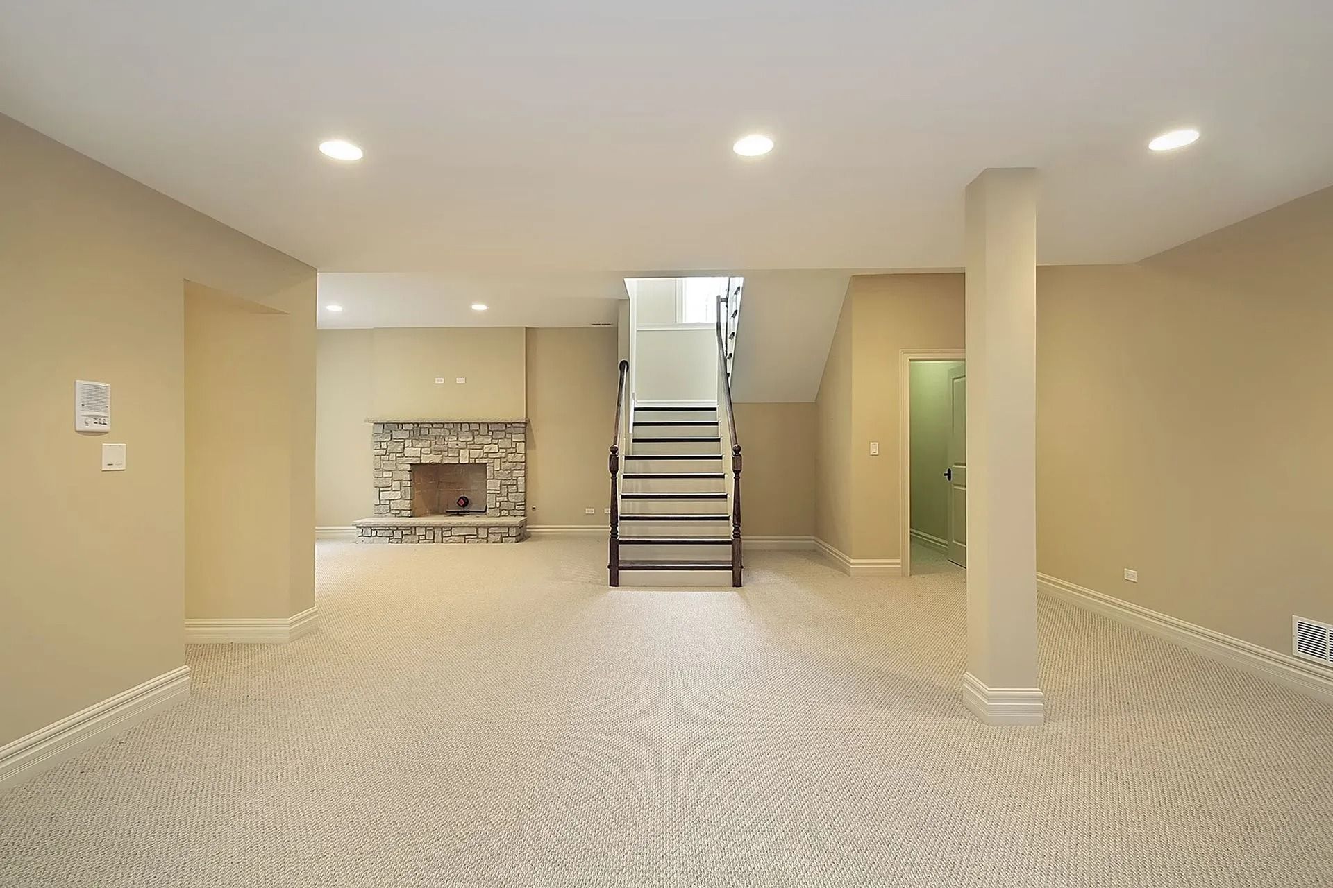Beige basement with carpet, fireplace, stairs, and recessed lighting.