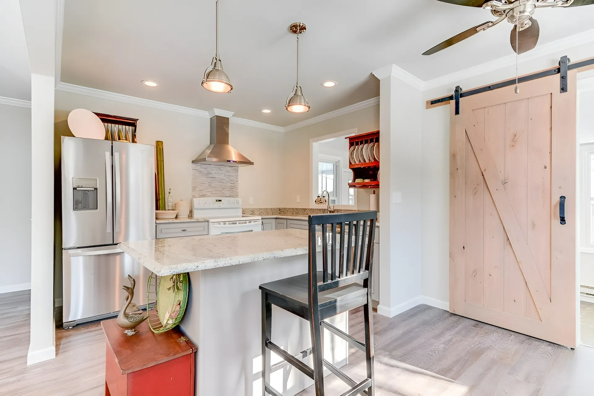 Kitchen with stainless steel appliances, breakfast bar with a stool, and a barn door.