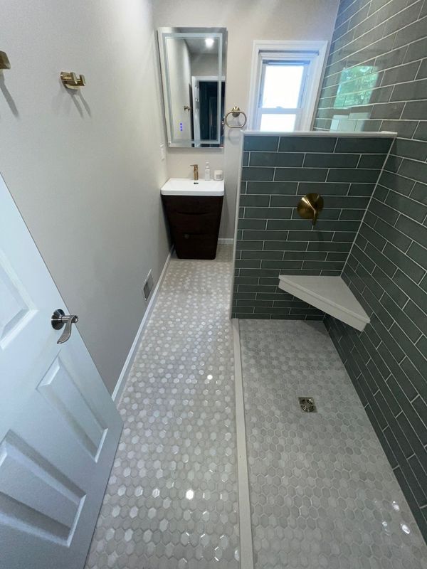 Newly renovated bathroom with gray tile shower and hexagon floor tiles.