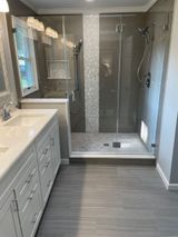 Modern bathroom with white vanity, gray tile floor, and glass shower.