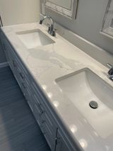 White double sink vanity with quartz countertop and two chrome faucets.