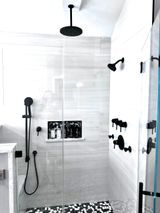 Modern shower with black fixtures and white marble-like tile.