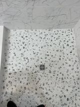 Shower with pebble tile floor and drain. Gray and white colors.