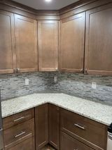 Kitchen cabinets in a corner with granite countertops and tan cabinetry.