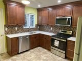 Kitchen with brown cabinets, stainless steel appliances, white countertops, and a mosaic backsplash.