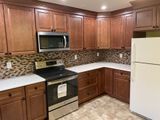 Kitchen with brown cabinets, stainless steel appliances, white countertops, and a mosaic backsplash.