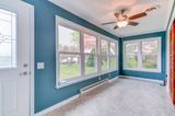 Sunroom with teal walls, large windows, and beige carpet.