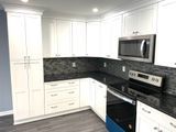 White kitchen cabinets with black countertops and appliances.