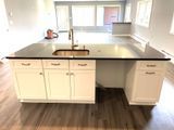 Kitchen island with white cabinets, dark countertop, and gold sink.