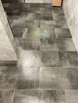 Gray, rectangular tile flooring in a bathroom, with a wood-grain pattern.