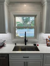 Kitchen sink with a window above, white cabinets, and subway tile backsplash.