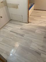 Bathroom floor tiled with light gray and white rectangular tiles. Walls partially unfinished.