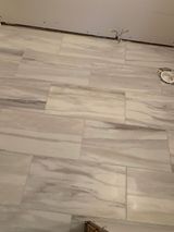 Light gray rectangular tiles on a floor, with a marble-like pattern.