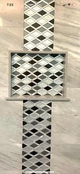 Tilework with diamond-patterned mosaic design in black, white, and gray, recessed in a larger, light-toned tile wall.