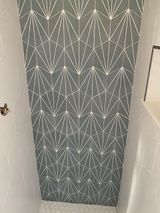 Gray and white geometric tile backsplash in a shower.