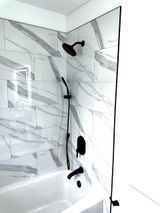 Black shower fixtures and white marble tile in a modern bathroom.
