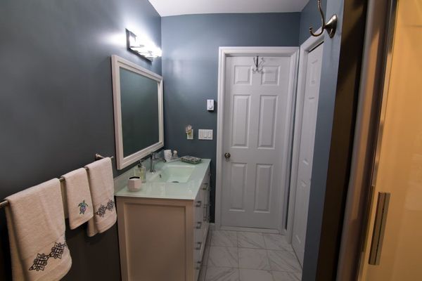 Bathroom with blue walls, white vanity, towels, mirror, and white door.