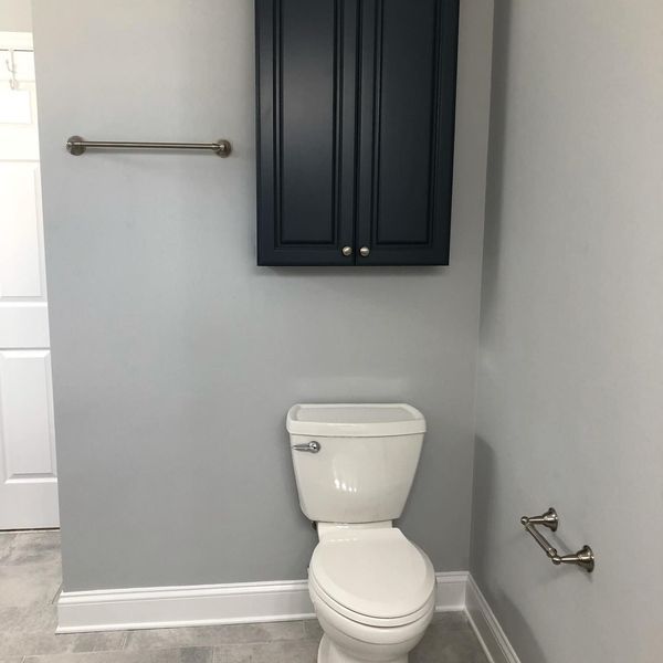 Bathroom with a blue cabinet above a toilet, gray walls, and a towel bar.