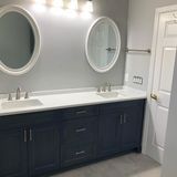 Navy blue vanity with white countertop, oval mirrors, and white sink basins.