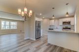 Open-concept living space with a kitchen featuring white cabinets, stainless steel appliances, and wood-look flooring.