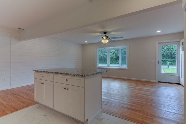 Interior of a newly renovated home with a kitchen island, hardwood floors, and a door leading outside.