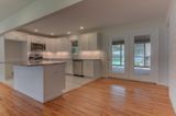 Modern kitchen with white cabinets, island, stainless steel appliances, and hardwood floors.