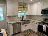 White kitchen with stainless steel appliances, light countertops, and cabinetry.