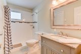 Bathroom with shower, vanity, toilet. Light blue vanity, patterned shower curtain.