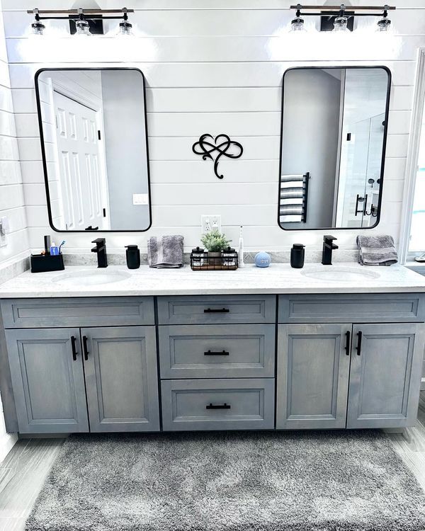 Bathroom with double vanity, gray cabinets, white countertop, black fixtures, and mirrors.