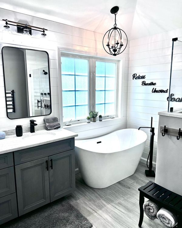 Modern bathroom with a white tub, gray vanity, and decorative lighting.