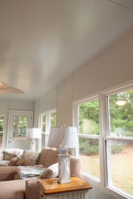 Sunroom interior with windows, neutral color palette, sofa, and lamps.