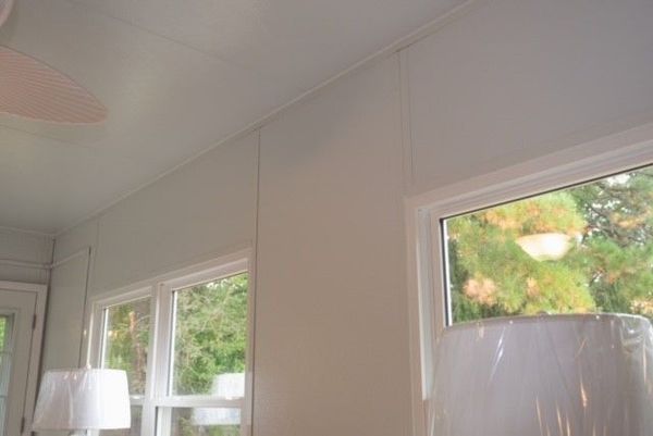 White room interior with windows, ceiling, and vertical wall paneling.