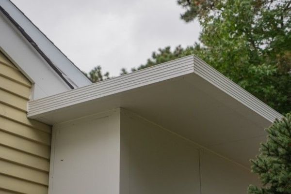 White overhang on a light-colored building, with horizontal siding on the adjacent wall.