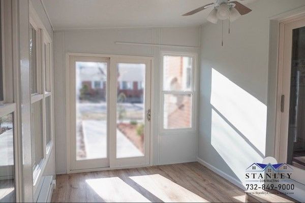 Sunroom with sliding glass doors and windows, light walls, and wood-look flooring.
