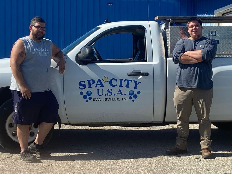 Two men stand by a white truck with 
