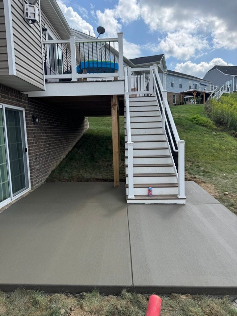 Backyard deck with white stairs leading to a concrete patio under a raised house