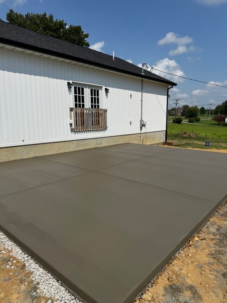 Freshly poured concrete driveway beside a white house on a sunny day