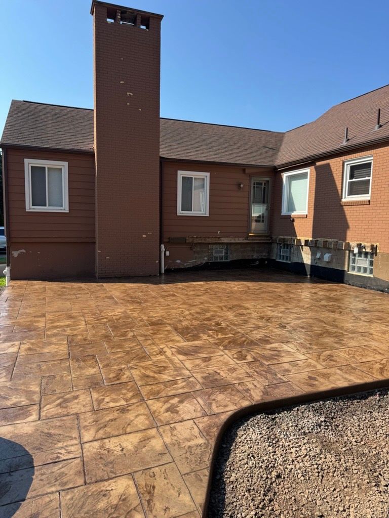 Brick house courtyard with stamped concrete patio and central chimney under a clear blue sky