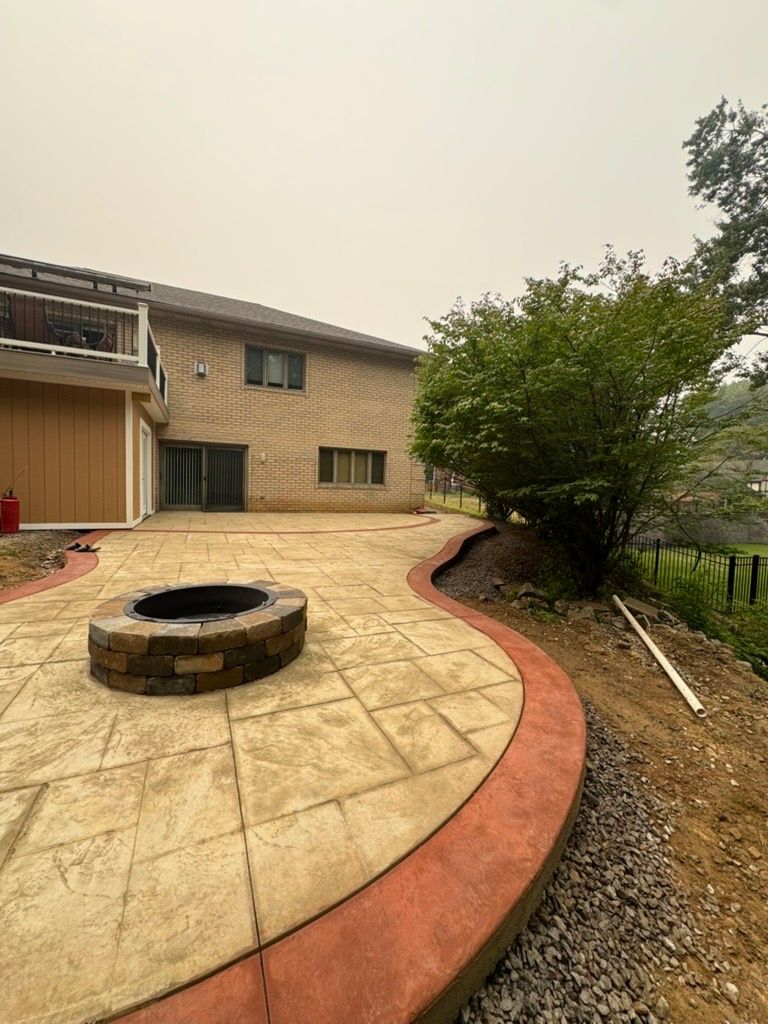 Backyard patio with curved stamped concrete, stone fire pit, and house exterior