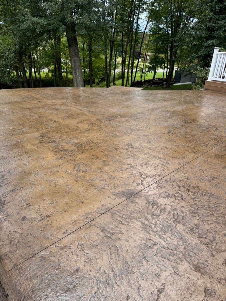 Wet concrete patio beside wooded yard and white railing