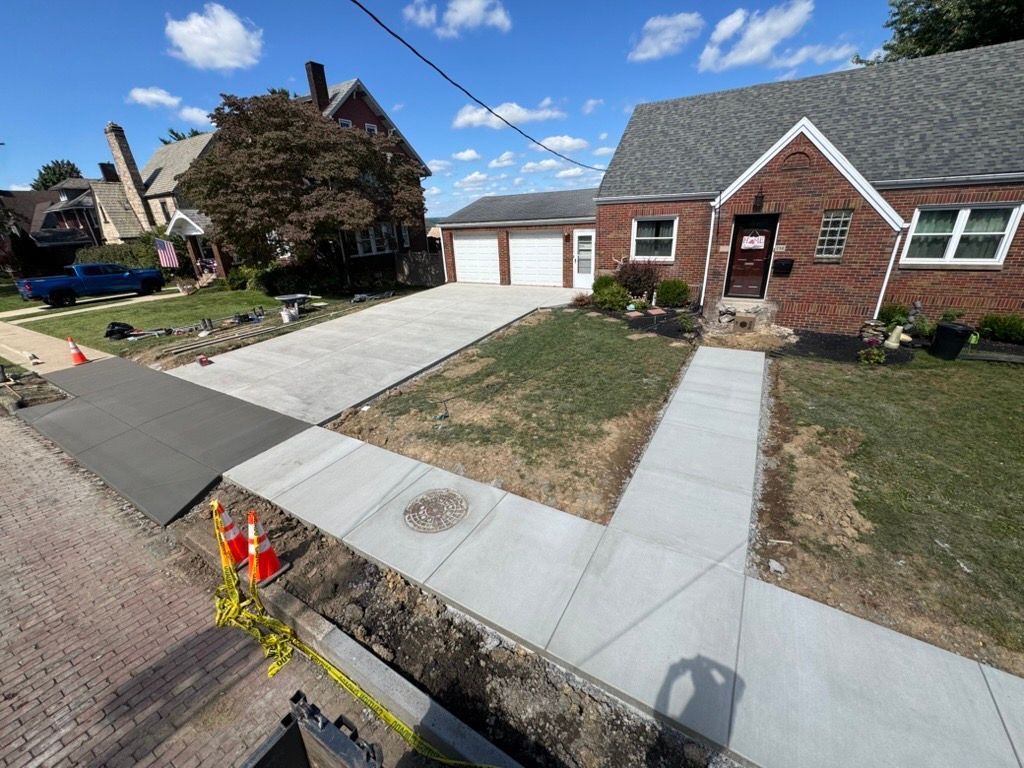 Suburban driveway and front walkway with fresh concrete beside a brick house and garage