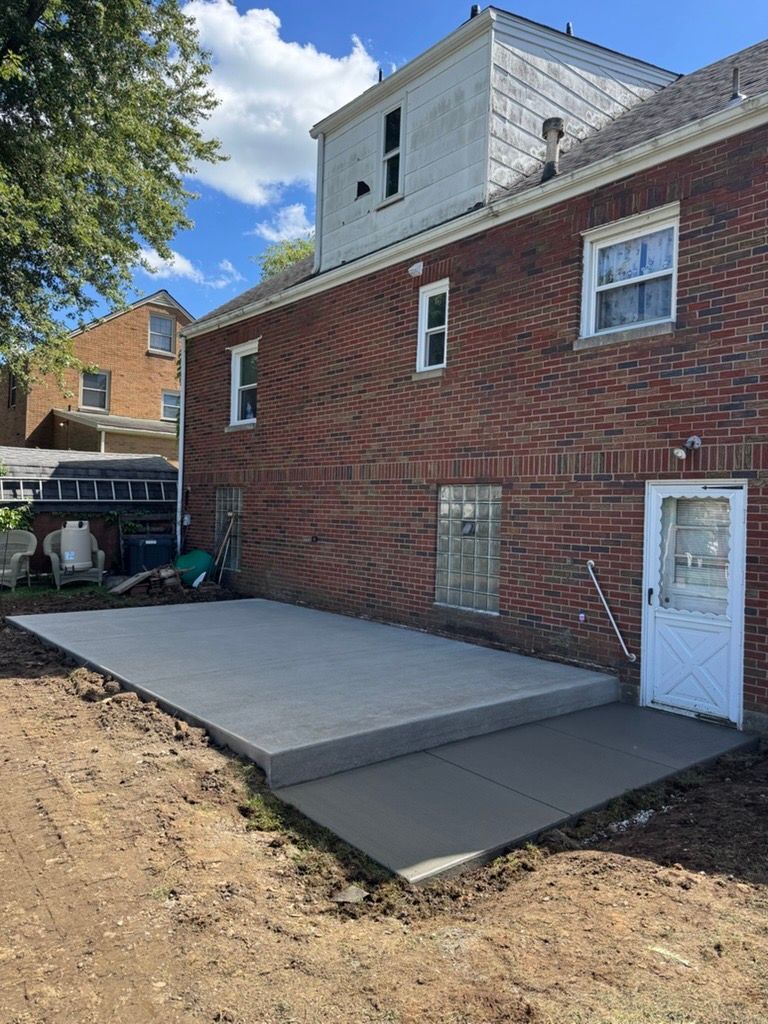 Brick house exterior with new concrete patio and side door under construction