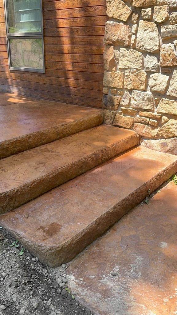 Stone steps leading to a brick and stone house entrance in warm sunlight.