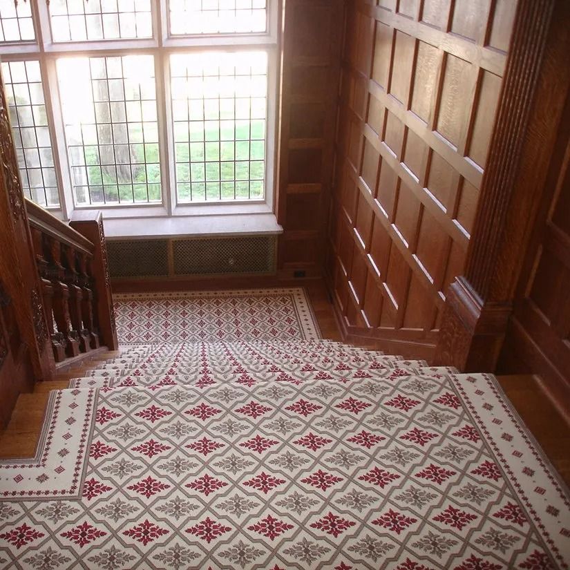 Staircase with patterned runner, wood paneling, and large window overlooking a yard.