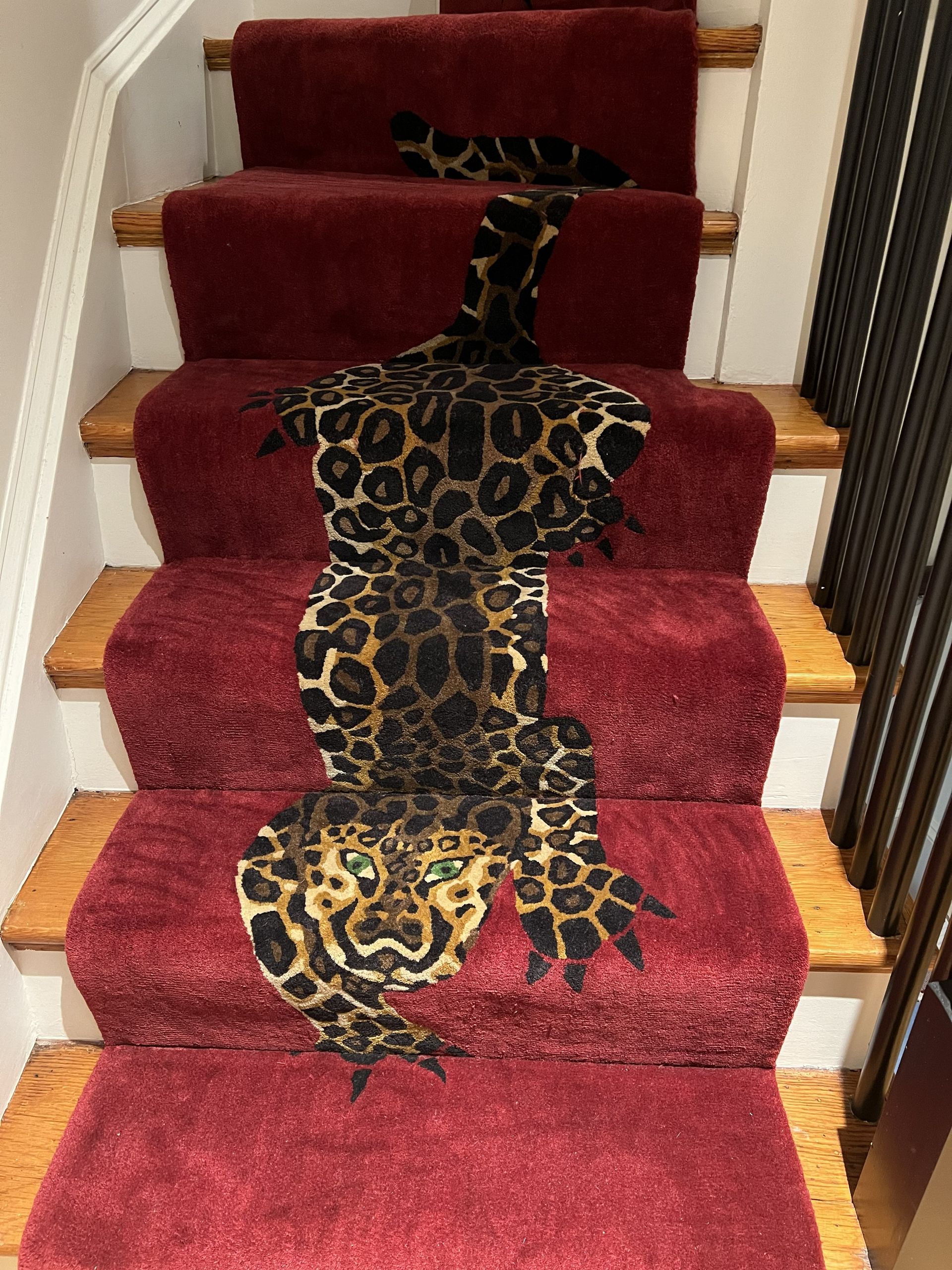 A leopard-print runner decorates a set of stairs carpeted in deep red, with a leopard face featured on the bottom step.
