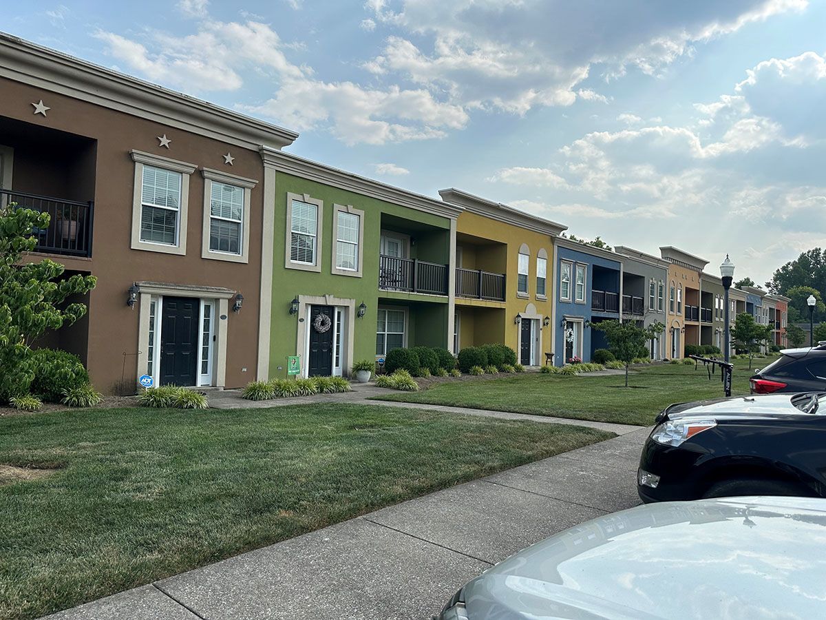 A row of colorful apartment buildings with cars parked in front of them.