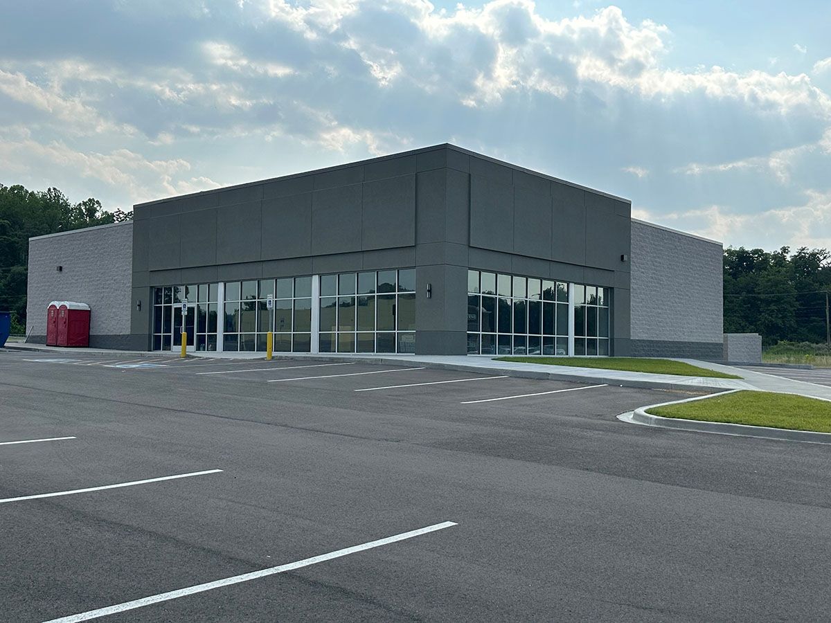 A large building with a lot of windows is sitting next to a parking lot.