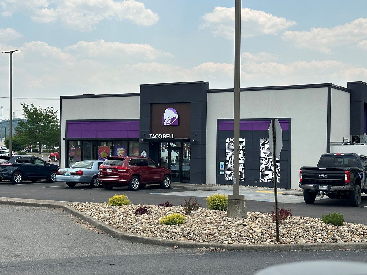 A taco bell restaurant with cars parked in front of it.